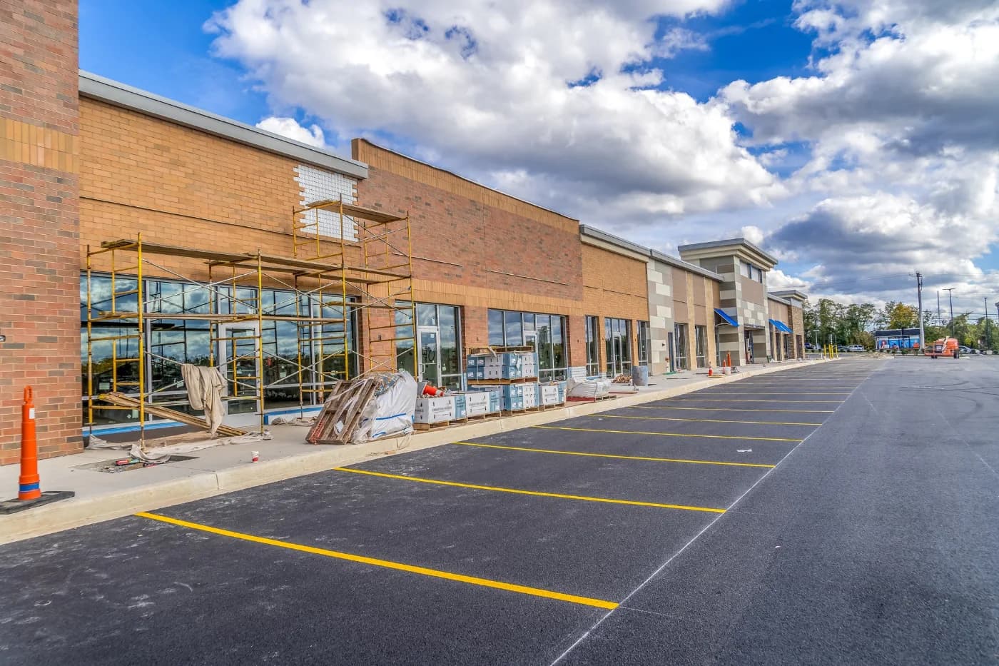 Brick retail center under construction with scaffolding along the storefront elevation