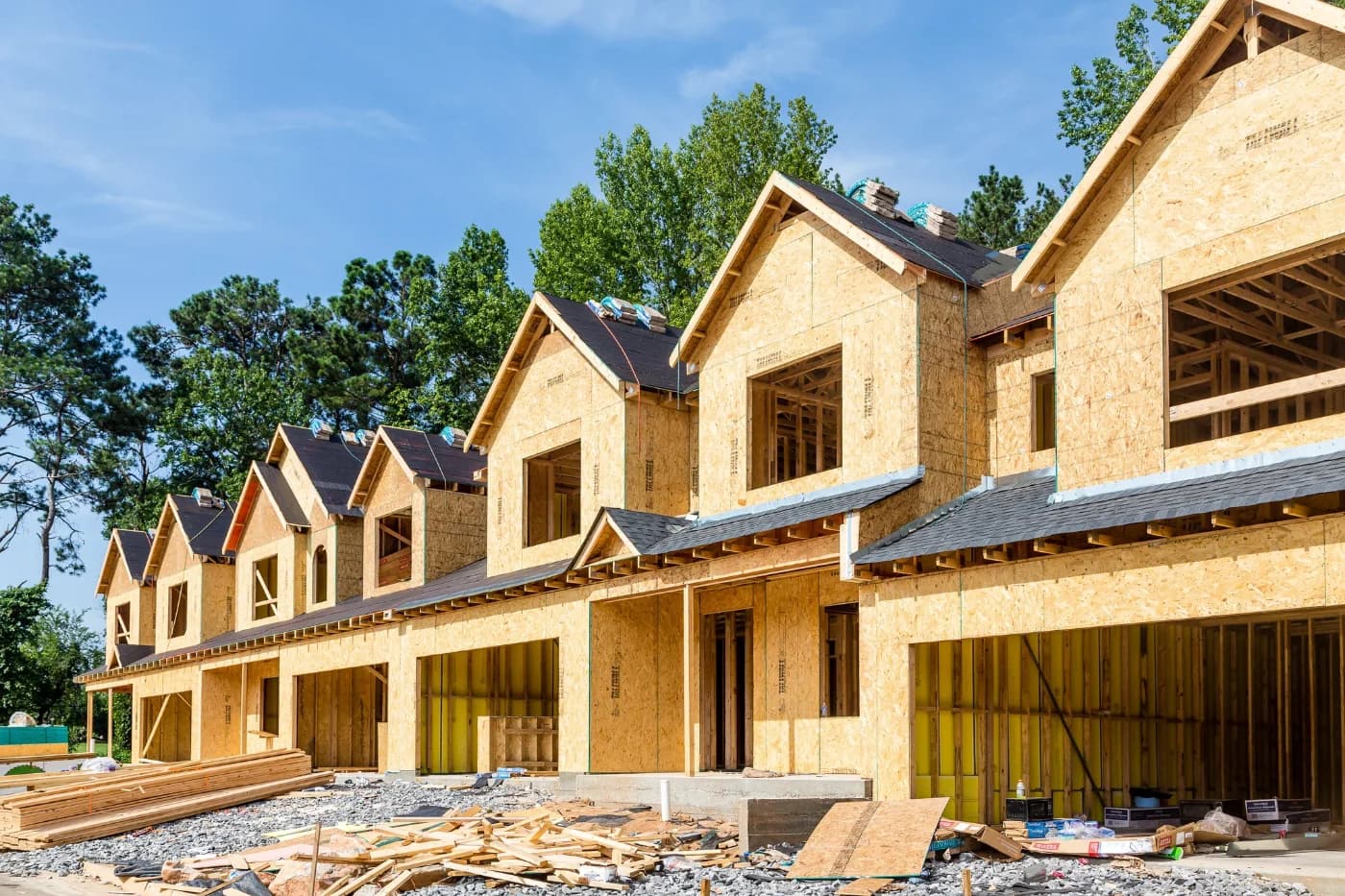 Row of new homes under construction with roof and wall framing exposed
